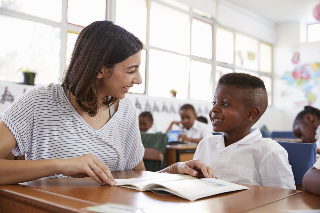 Teacher and student at desk. Both are smiling