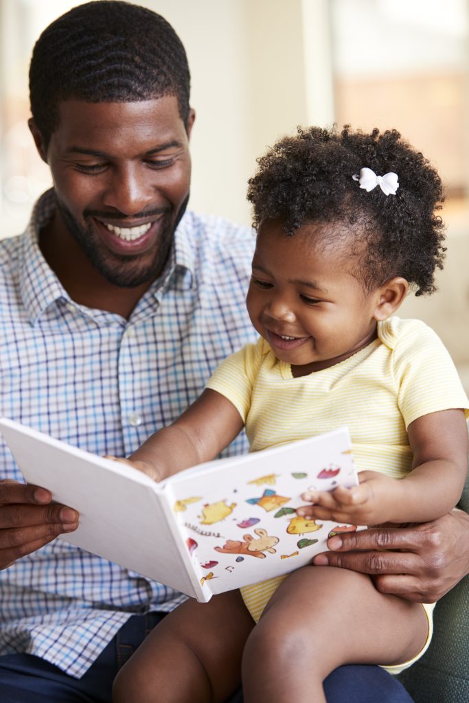 father reading with toddler daughter