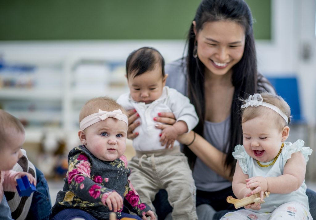 Montessori infant environment. Caregiver and four infants sitting together