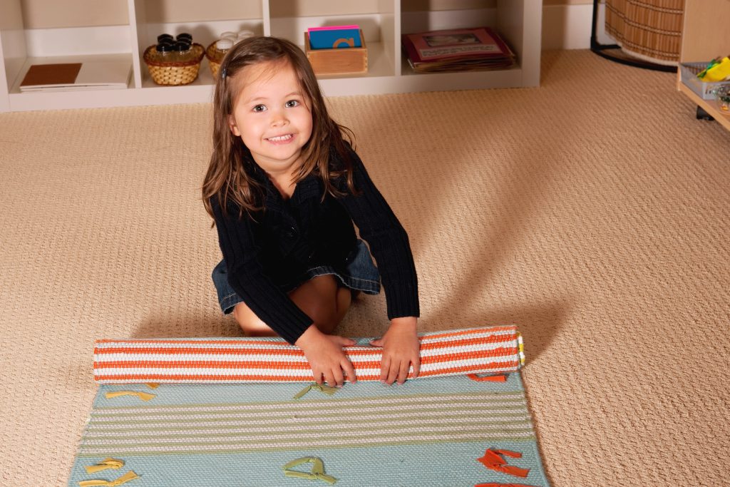child rolling a mat in the Montessori environment