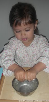 NAMC Montessori preschool practical life activities pouring water girl wringing cloth
