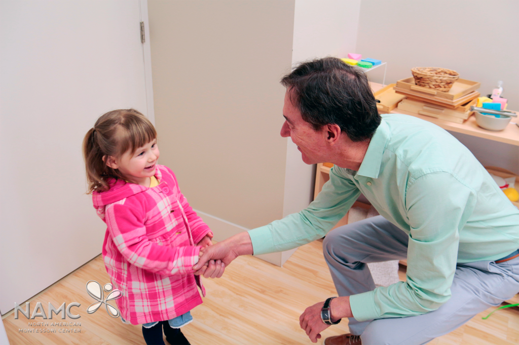 Montessori teacher and toddler shaking hands at morning greeting