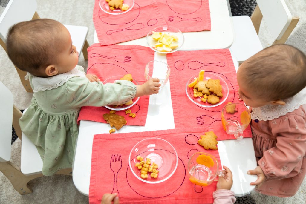 Toddlers sitting at table eating snacks in Montessori environment