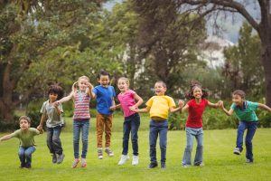 Group of children outside holding hands and jumping