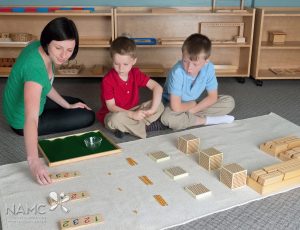 Montessori students and teacher adding with the Golden Bead Material
