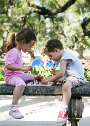 NAMC summer vacation ideas for Montessori families children play chess in garden