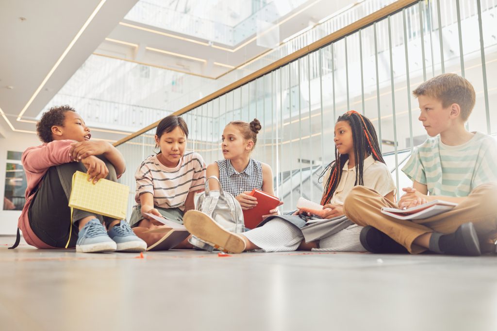Group of elementary students sitting on floor and telling stories