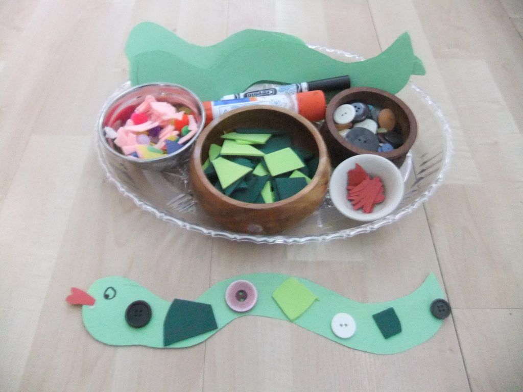 materials to make a button snake; felt pieces, markers, foam pieces, buttons, cut out of snake and tongue, finished button snake