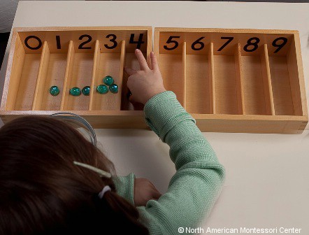 child placing counters in Montessori Spindle Boxes