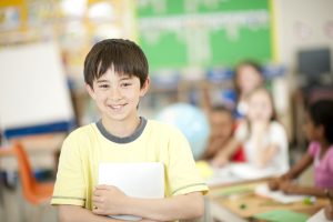 Elementary student holding journal, smiling at camera