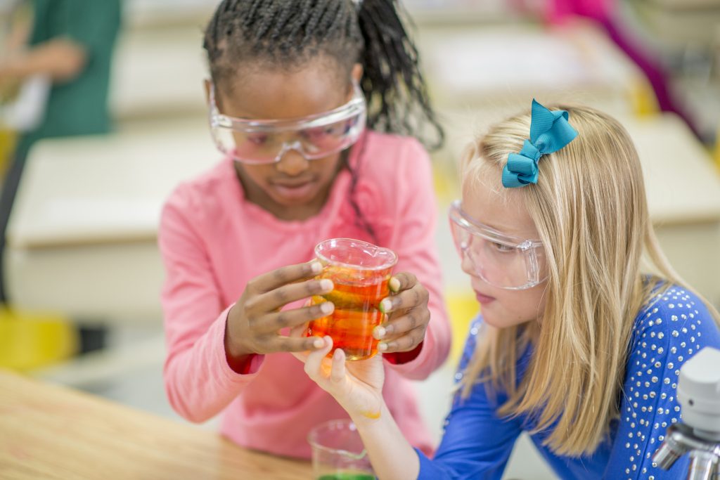 Montessori elementary students wearing safety glasses during a chemistry experiment