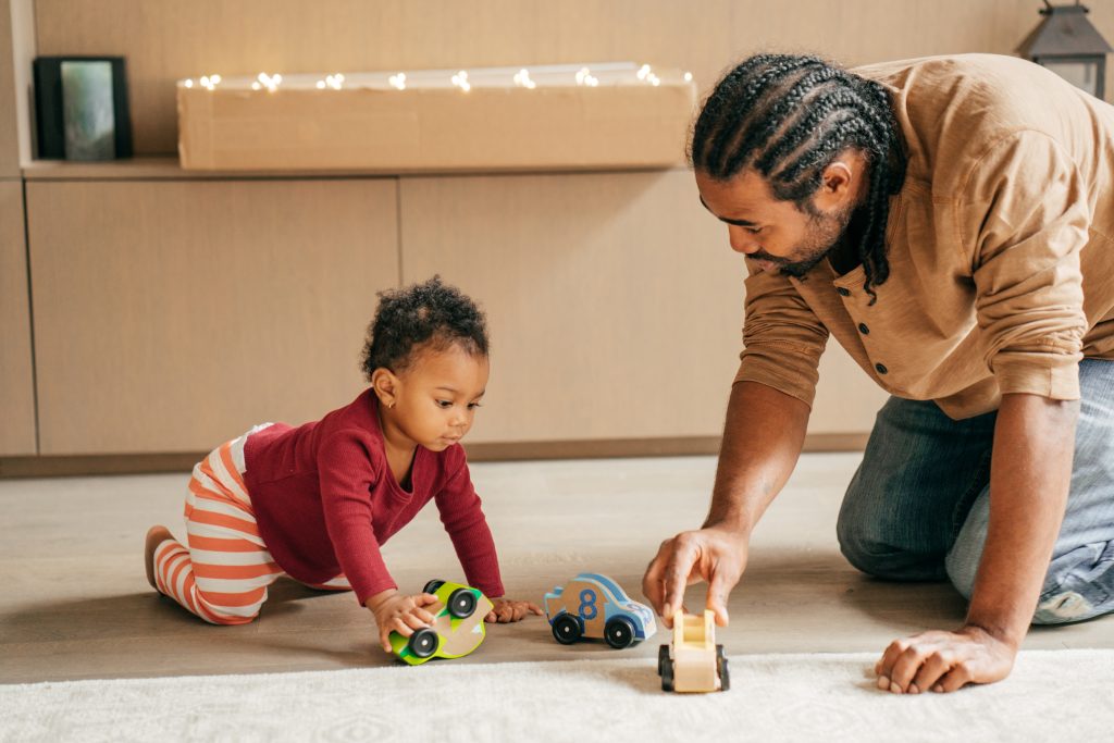 father and toddler playing cars on carpet