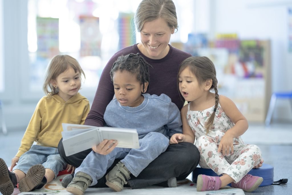 Storytime at the library. Librarian reading to three preschool age children