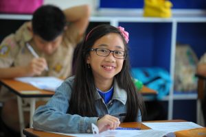 Student smiling at camera working at table