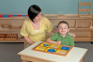 Montessori teacher and child working with the Geometric Demonstration Tray