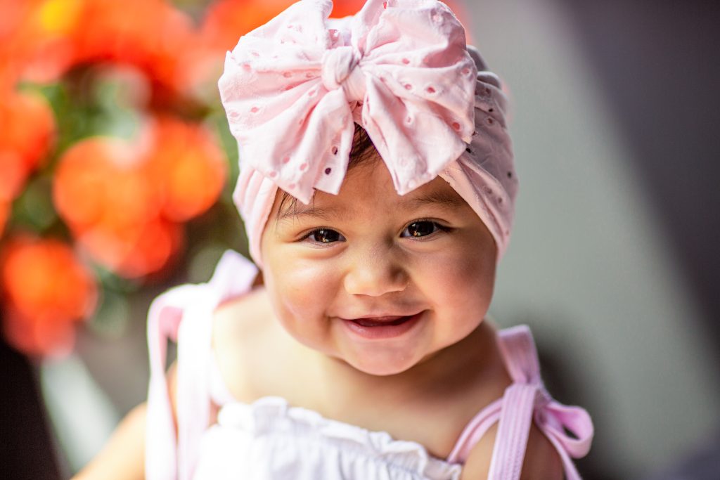 Infant smiling at camera. Pink scarf around their head