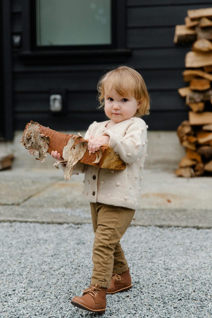 toddler carrying heavy stack of wood