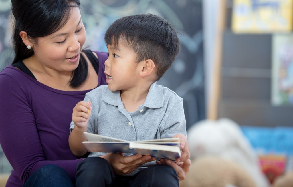 Two year old child sitting on teacher's lap and having a conversation