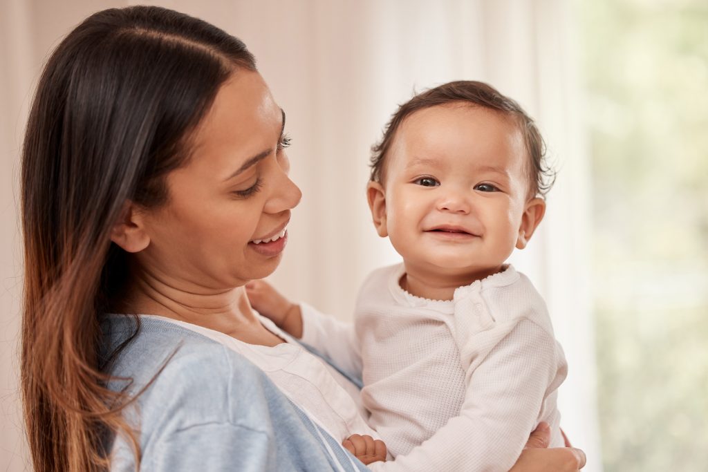 Mother holding infant, who is smiling at camera