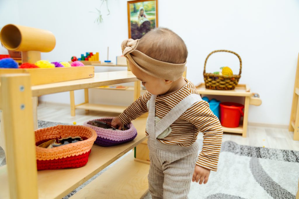toddler selecting material from basket on shelf in the Montessori classroom
