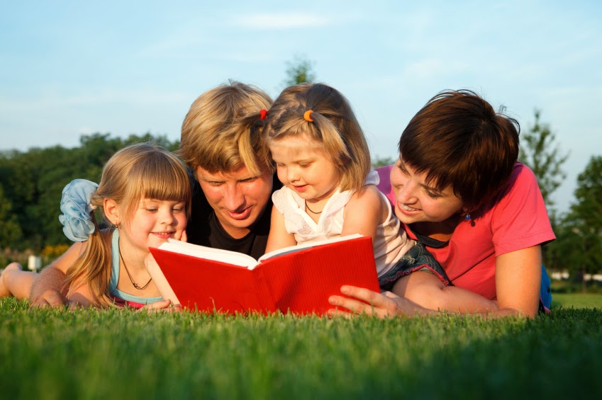NAMC montessori summer learning ideas follow the child. Family reading on grass