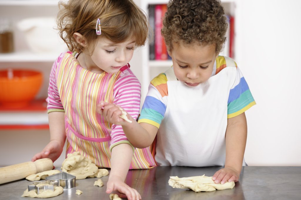 Two children rolling dough