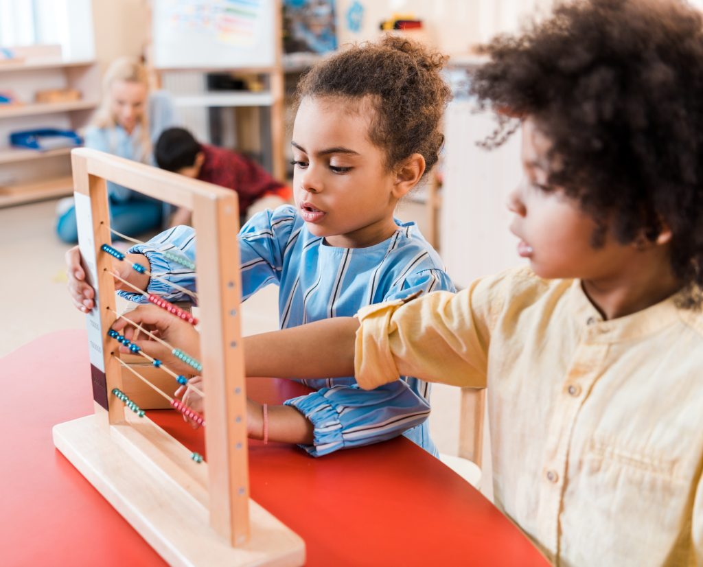 two Montessori students working with bead frame