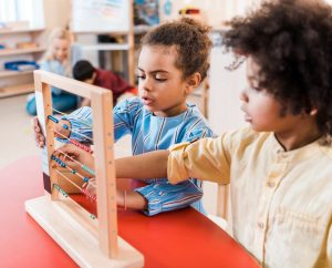 two Montessori students working with bead frame