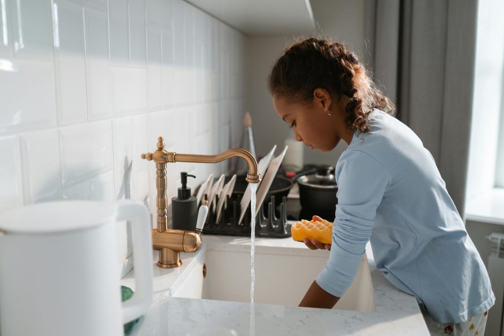 Elementary age student washing dishes