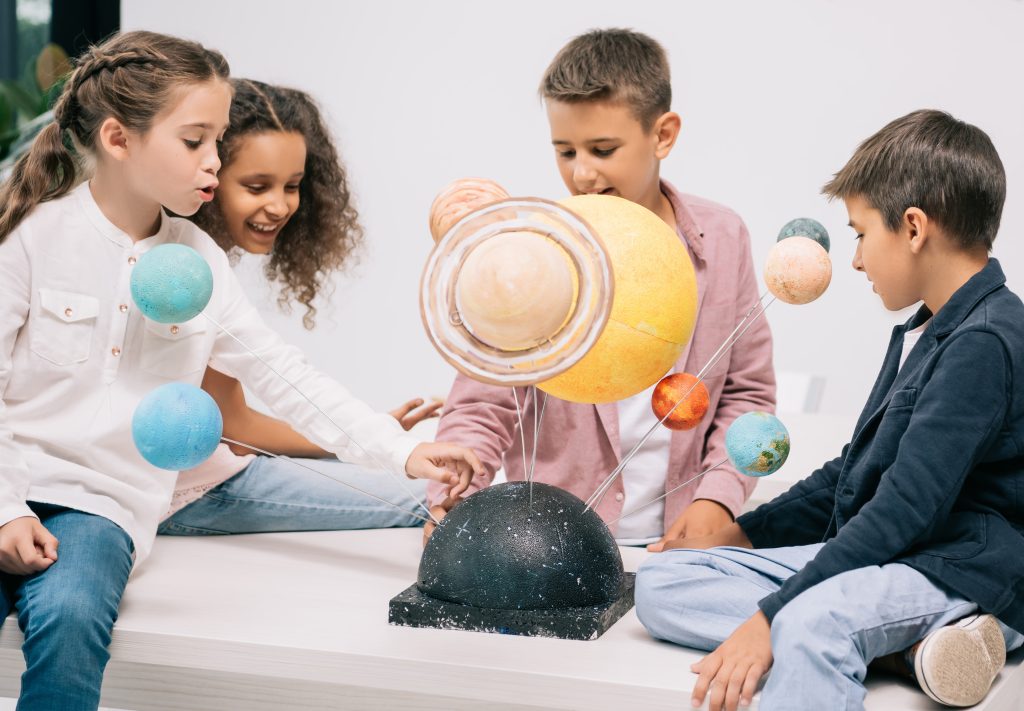 Group of elementary students looking at interactive model of the galaxy