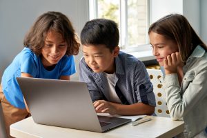 Three elementary students looking at laptop