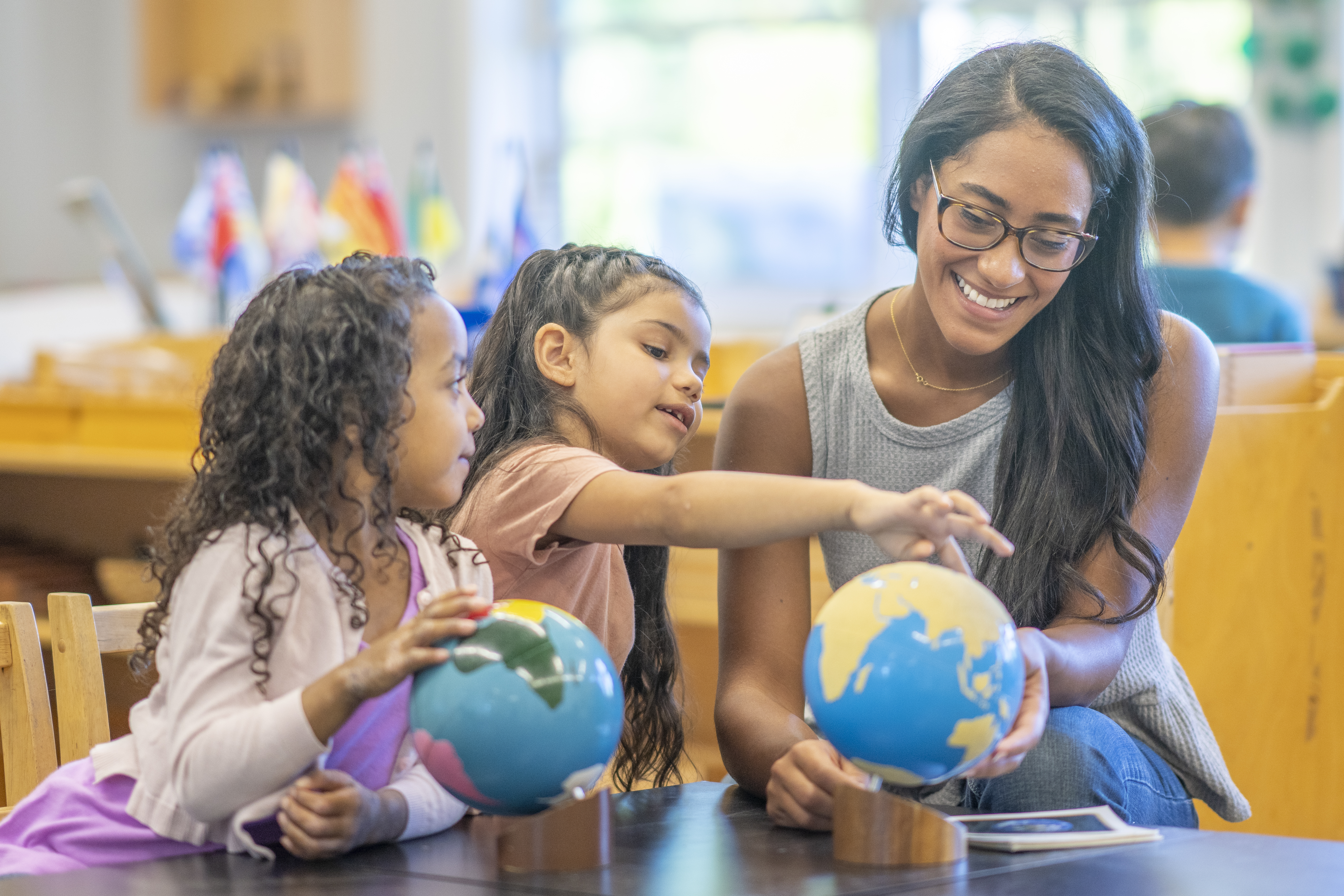 Montessori teacher and two students looking at sandpaper and colored globes