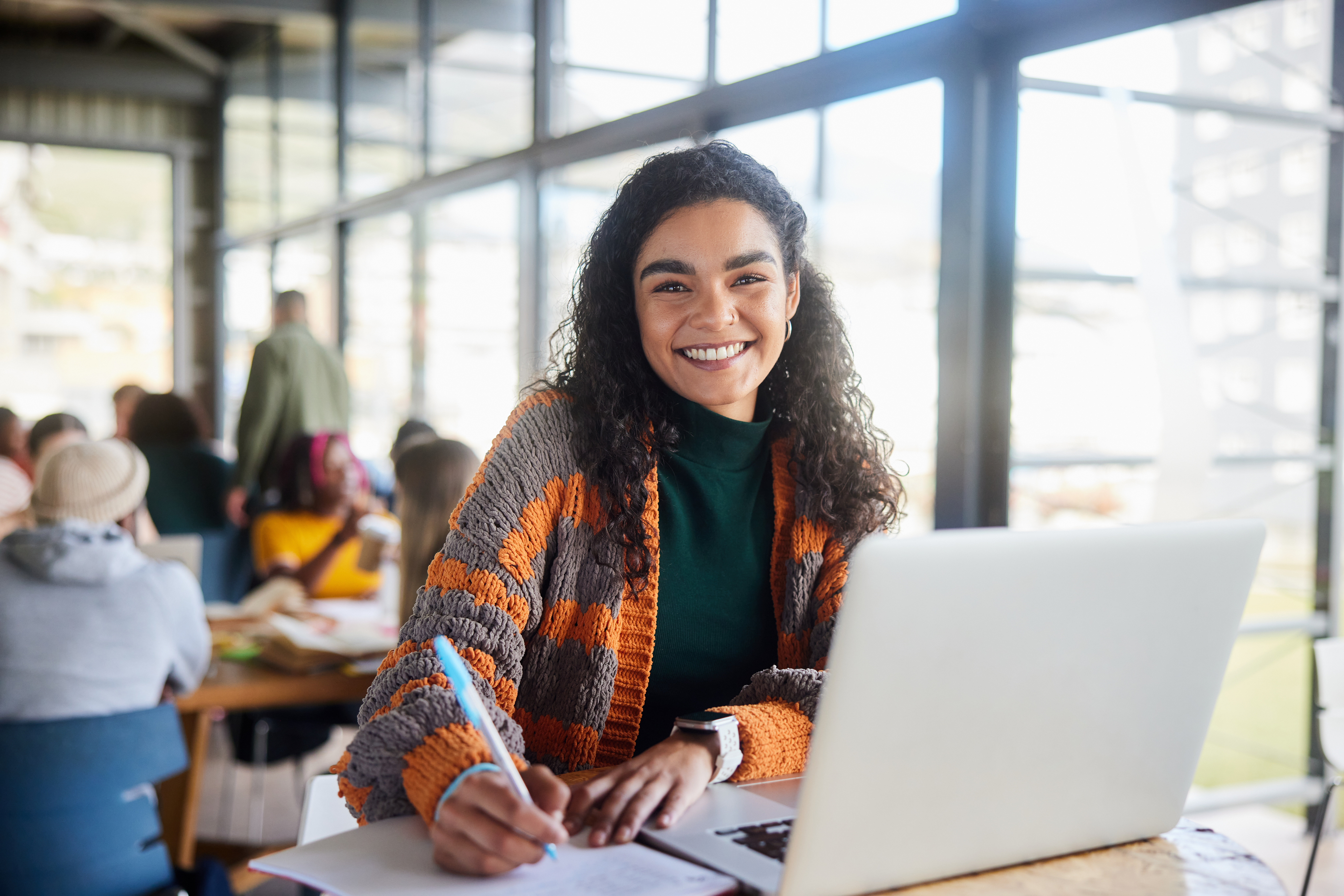 Young female student smiling while doing homework in a campus cafeteria